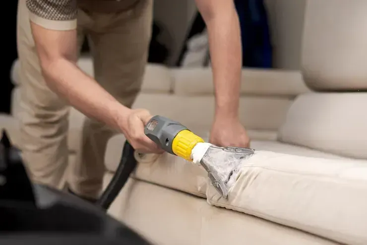 A man is cleaning the interior of a car with a vacuum cleaner.