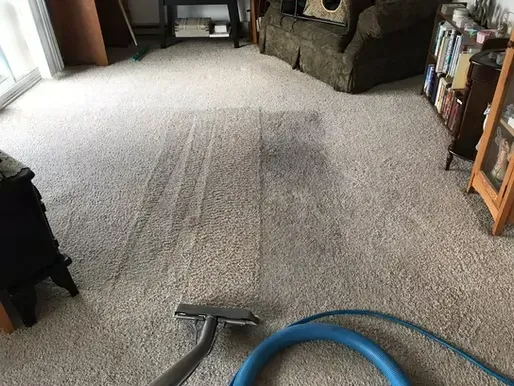 A vacuum cleaner is being used to clean a carpet in a living room.