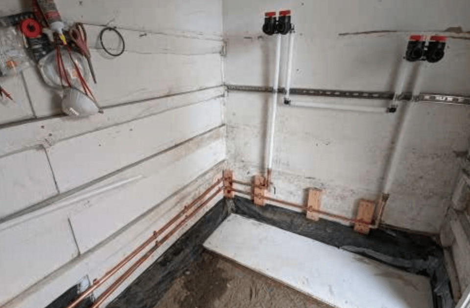 A room with a lot of pipes and tools on the wall.