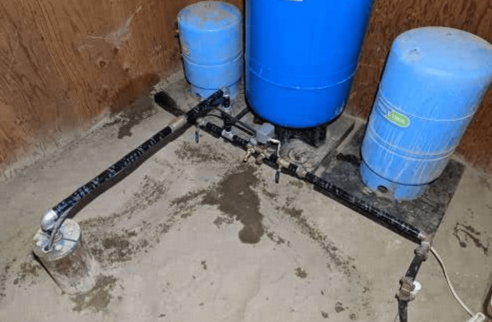 Two blue water tanks are sitting on the floor in a room.