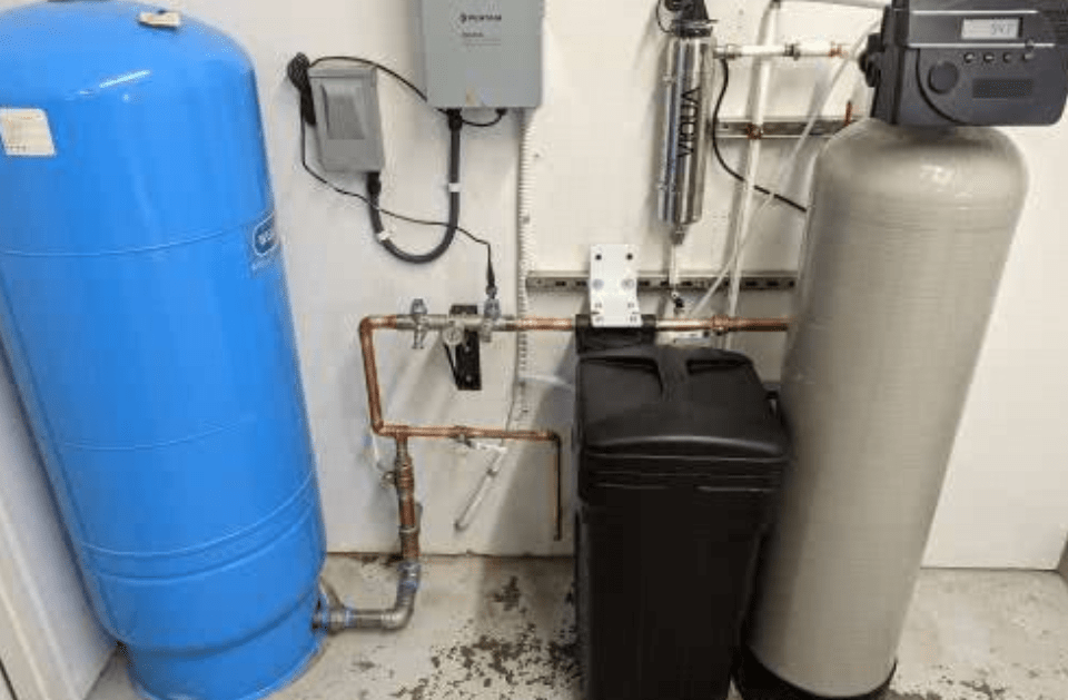 A water tank and a water softener are sitting next to each other in a room.