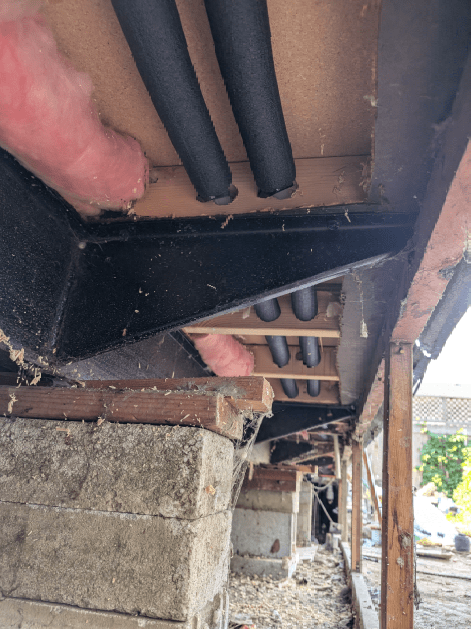 A person is standing under a roof with pipes coming out of it.