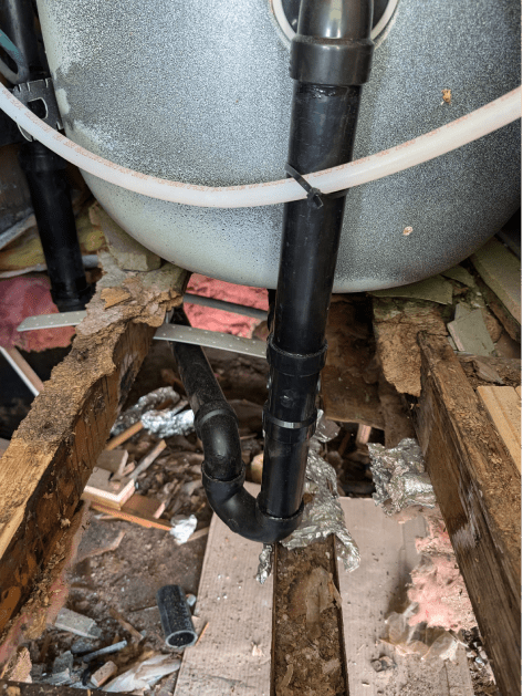 A black pipe is connected to a bathtub in a bathroom