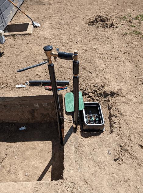 A hose is sitting in the dirt next to a box.