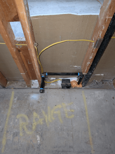 A pipe is being installed in a room under a wooden frame.