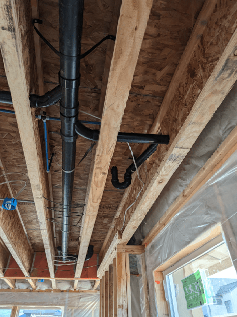 A pipe is hanging from the ceiling of a house under construction.