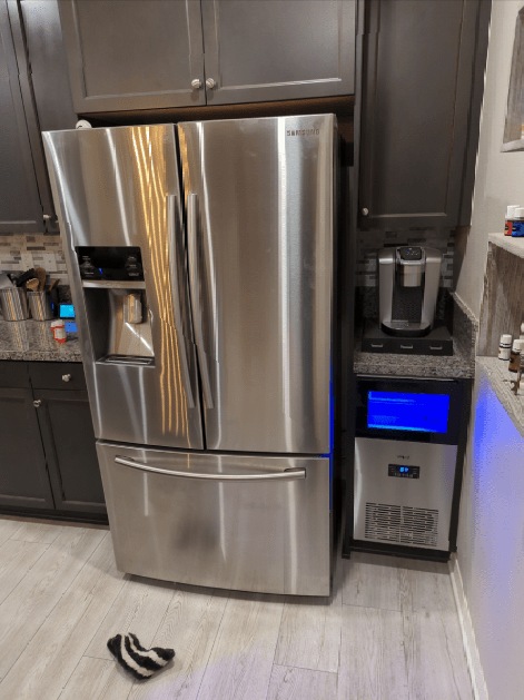 A stainless steel refrigerator is sitting in a kitchen next to a coffee maker.