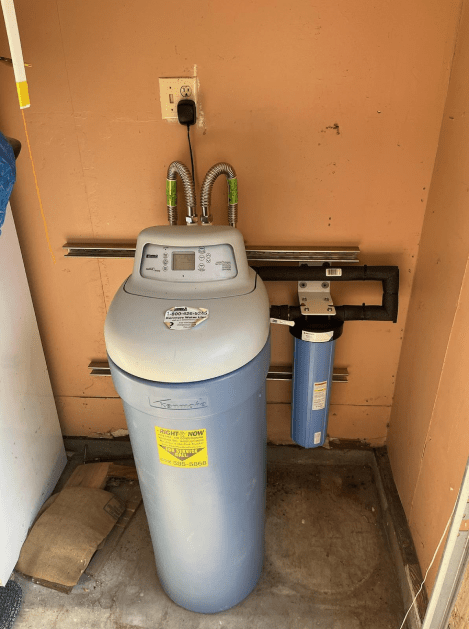 A blue water softener is sitting in a corner of a room.
