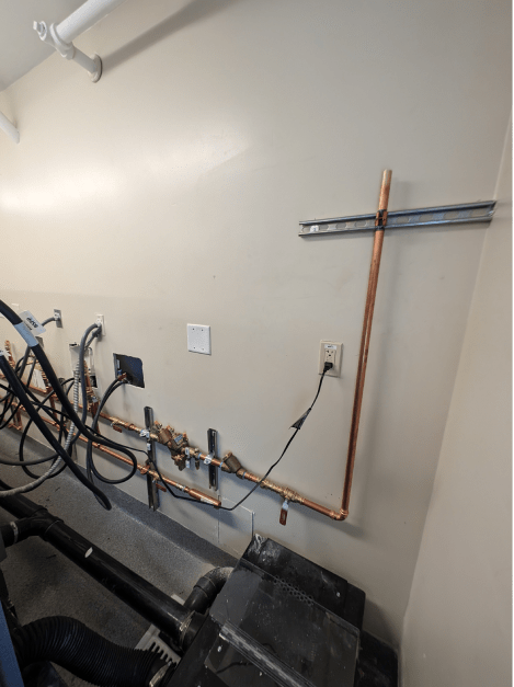 A room with a copper pipe hanging from the wall