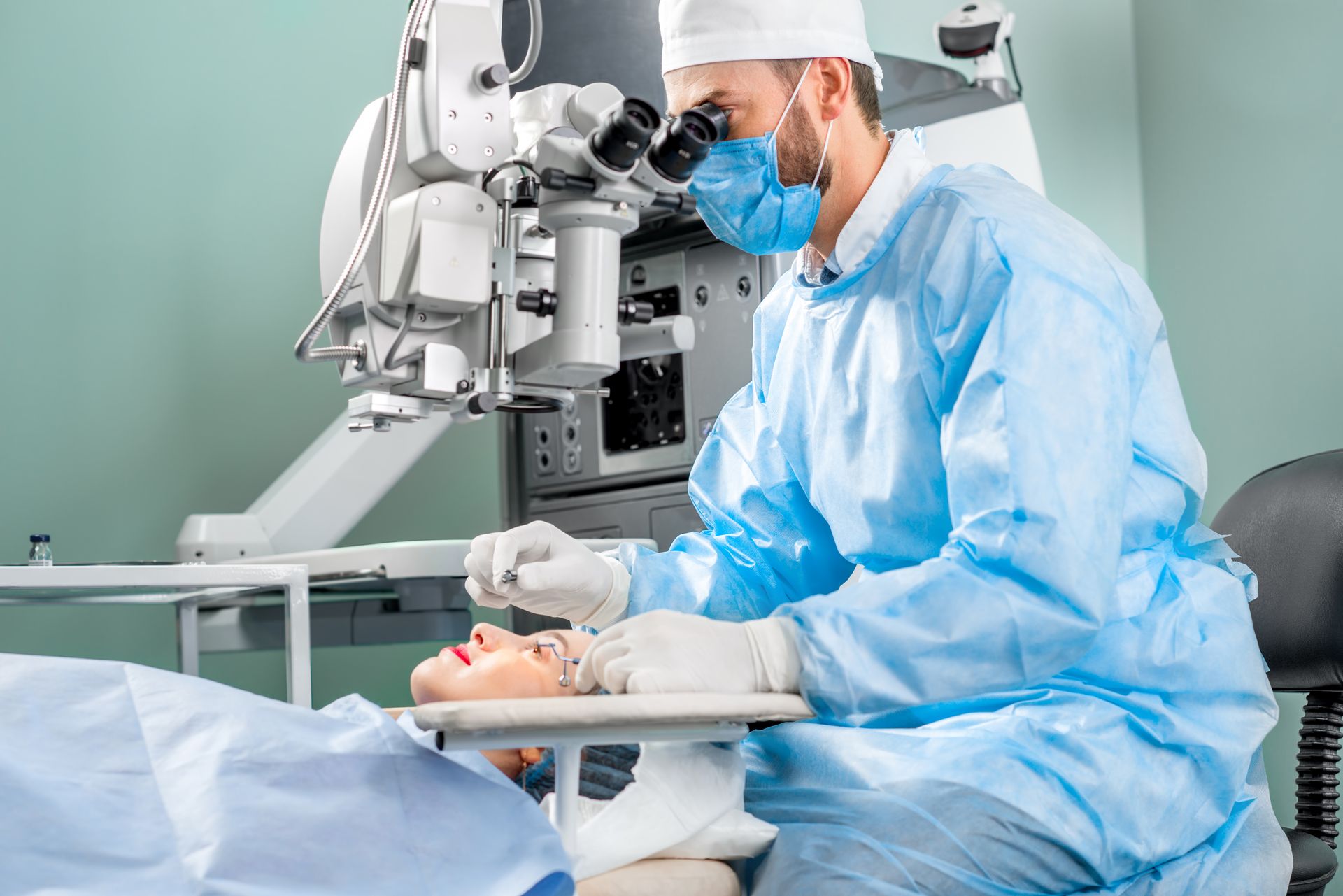 A surgeon performing an eye procedure with ophthalmic equipment in a sterile operating room area