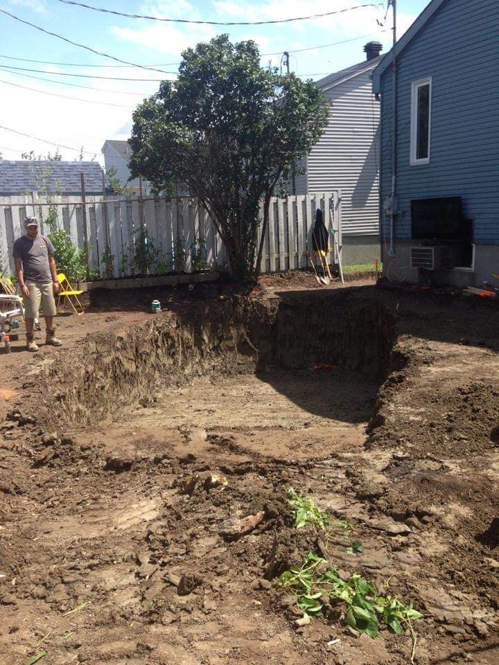 Un homme se tient debout dans la terre devant une maison.