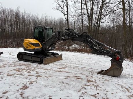 A yellow and black excavator is sitting in the snow.