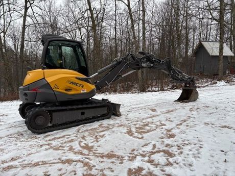 A yellow and gray excavator is parked in the snow.