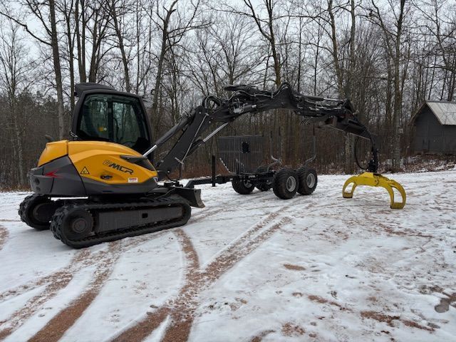 A yellow and gray excavator with a crane is parked in the snow.