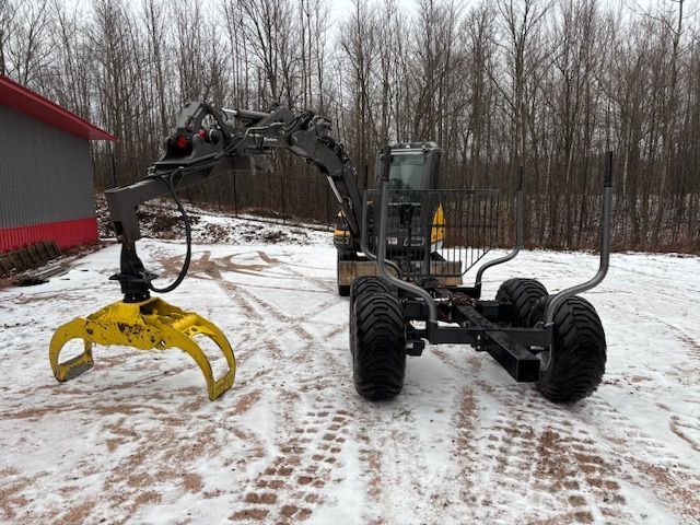 A tractor with a crane attached to it is parked in the snow in front of a building.