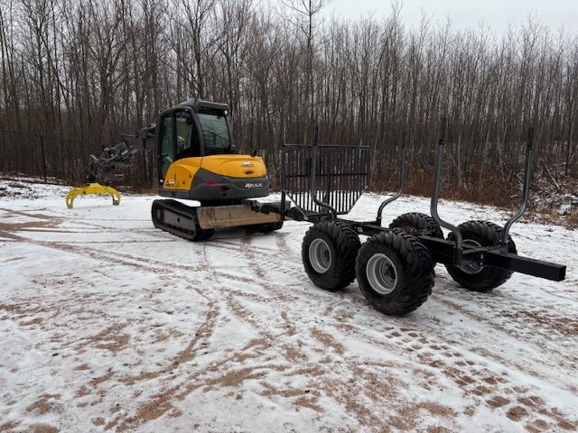 A yellow excavator is pulling a trailer in the snow.