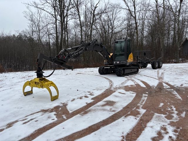 A black and yellow excavator with a crane is parked in the snow