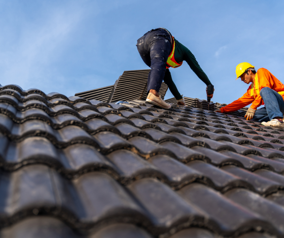 Two men are working on a tiled roof.