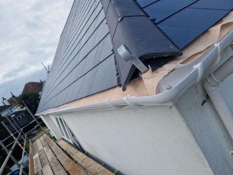 A house with a gutter on the side of it and a roof.