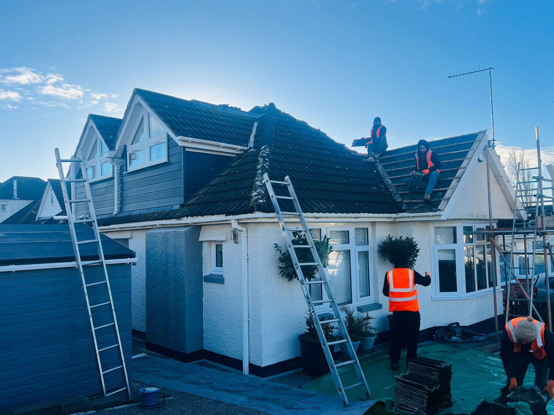 A group of people are working on the roof of a house.