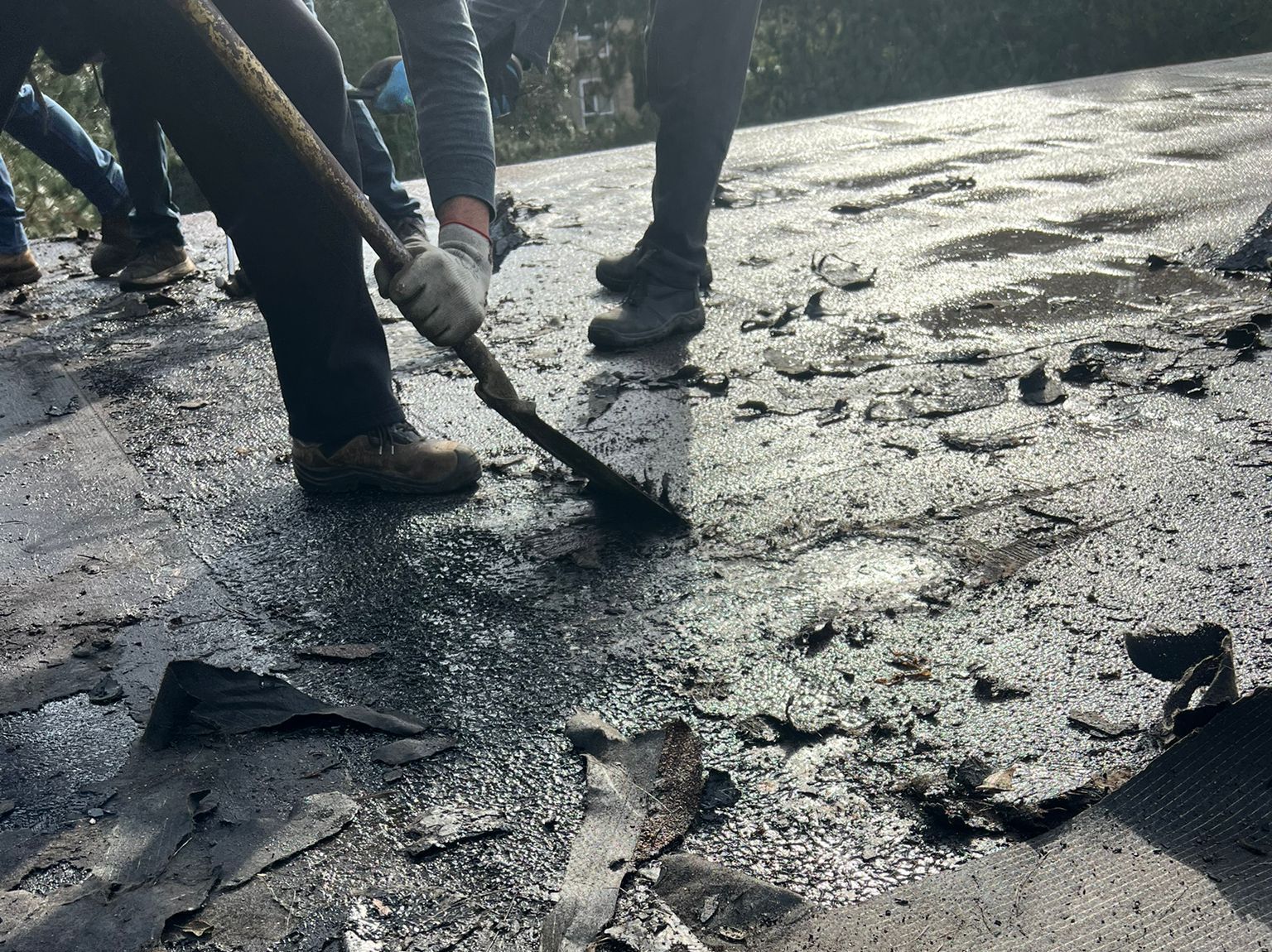 A group of people are working on a roof with a broom.