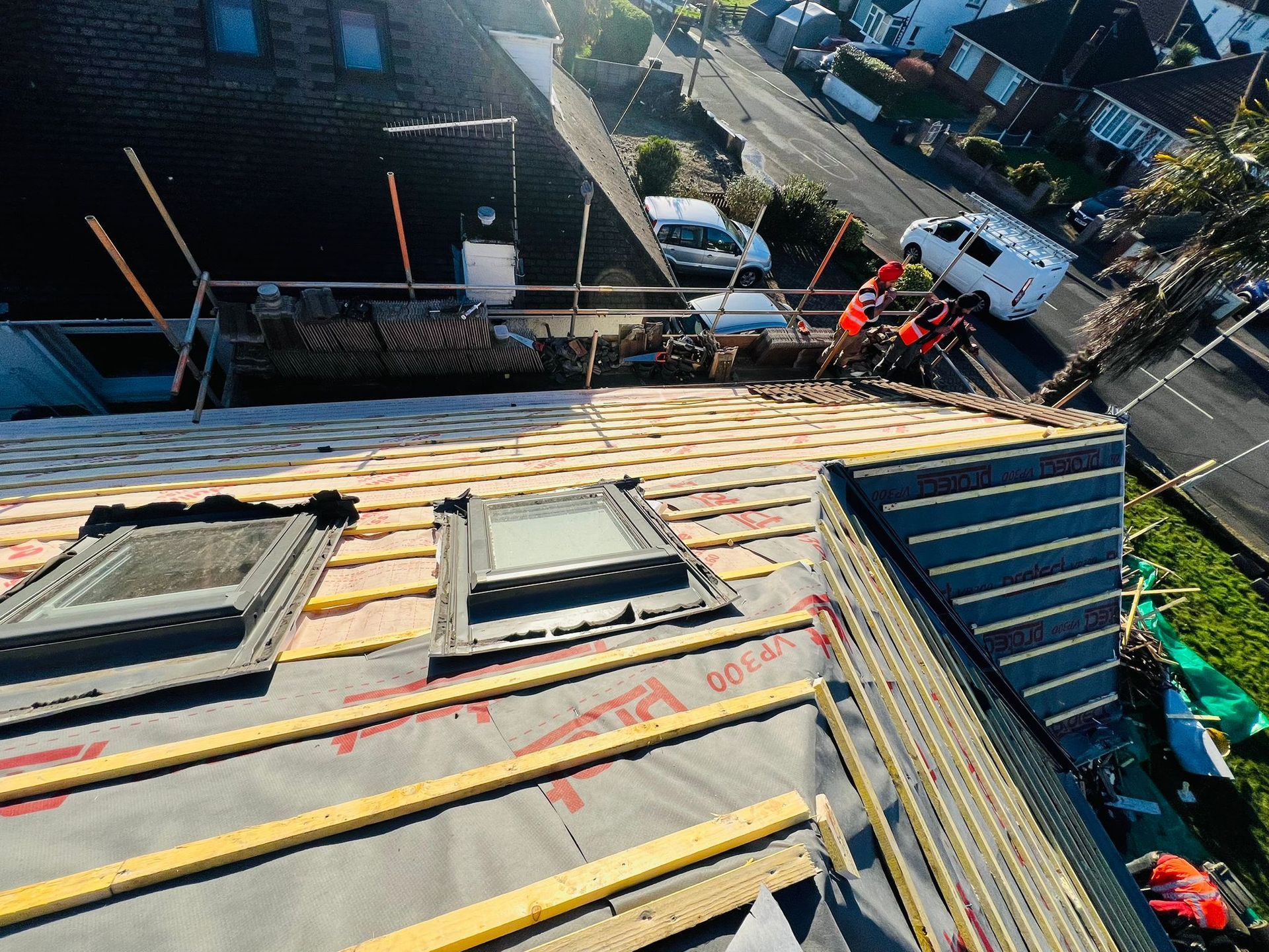 An aerial view of a roof with skylights being installed.