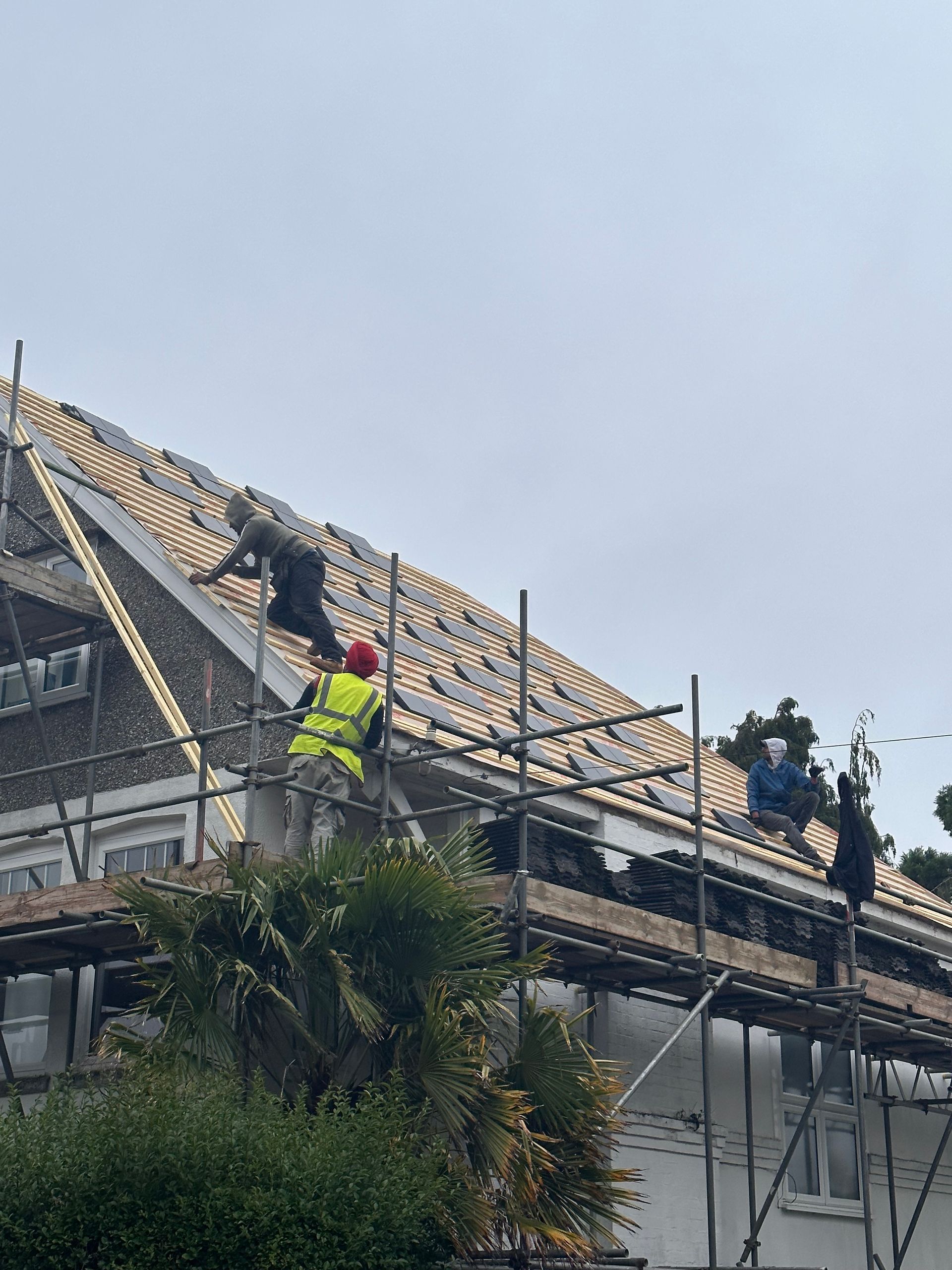 A group of construction workers are working on the roof of a building.