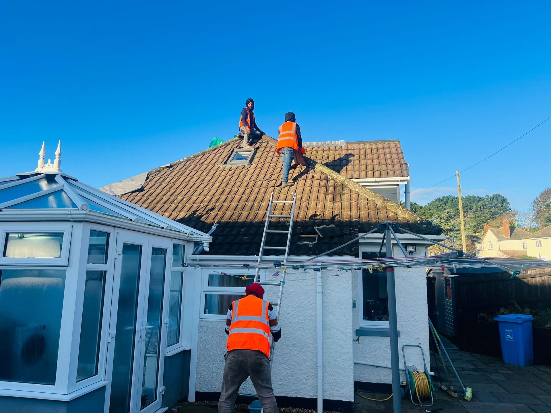 A group of people are working on the roof of a house.