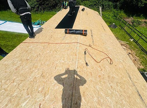 A man is standing on top of a wooden roof.