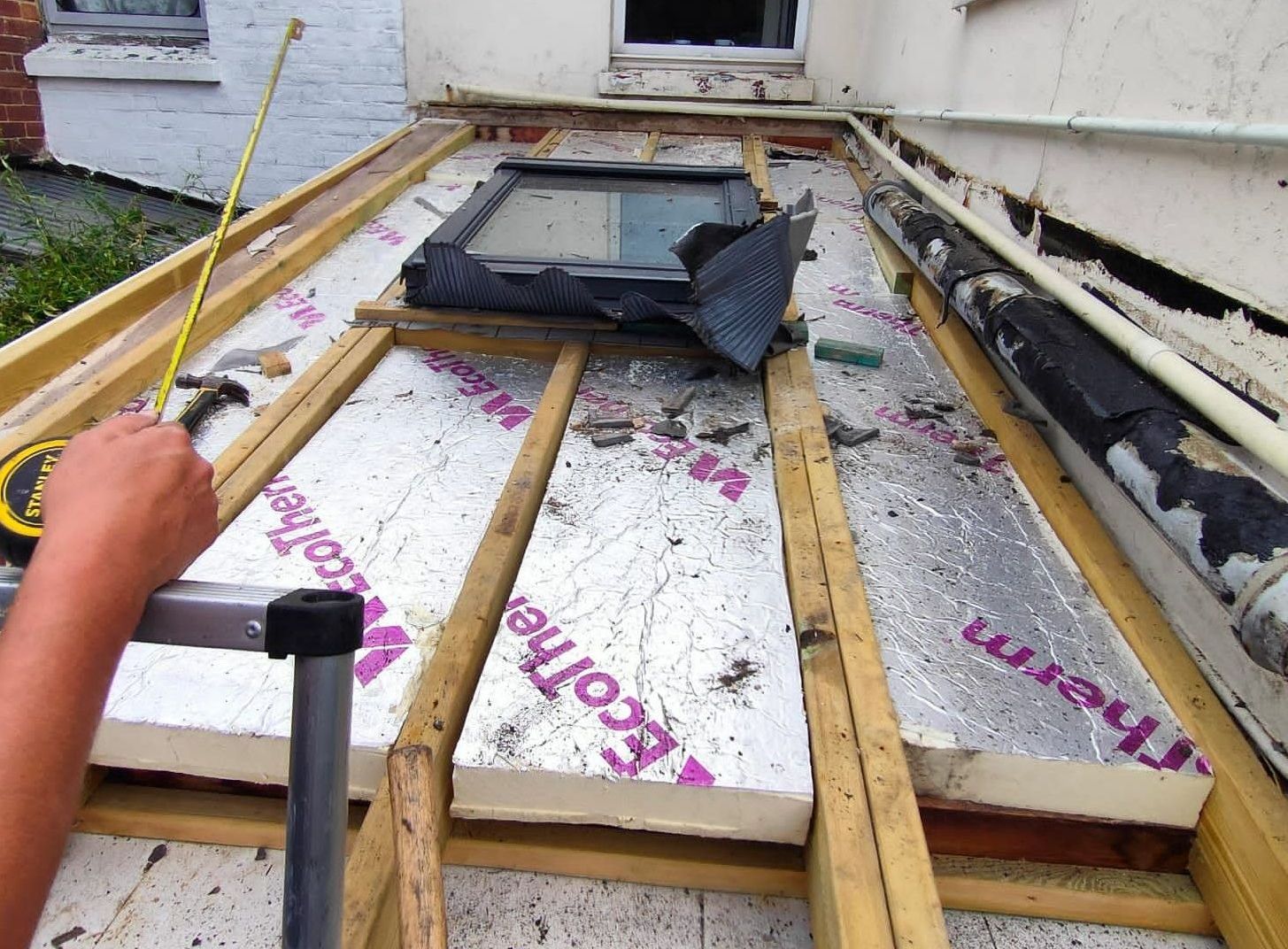 A person is measuring a roof with a tape measure