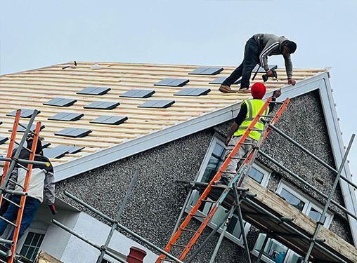 A group of construction workers are working on the roof of a building.