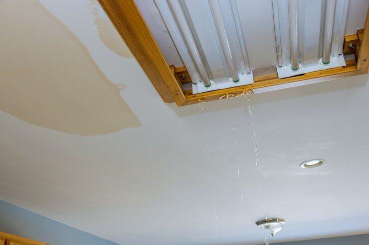 A ceiling with water coming out of it and a light fixture.