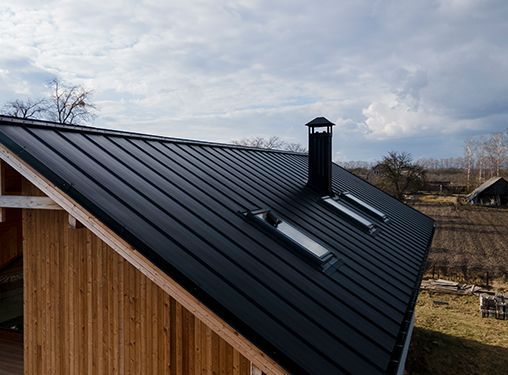 A wooden house with a black roof and two skylights.