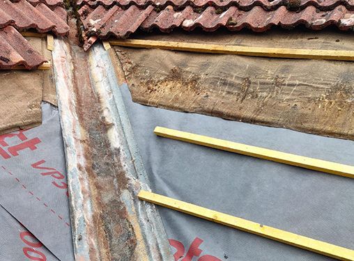 A roof is being repaired with wooden beams and shingles.