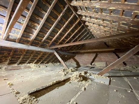 An attic with wooden beams and a brick wall.