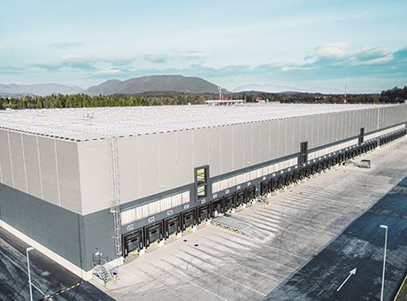 An aerial view of a large warehouse with trucks parked in front of it.