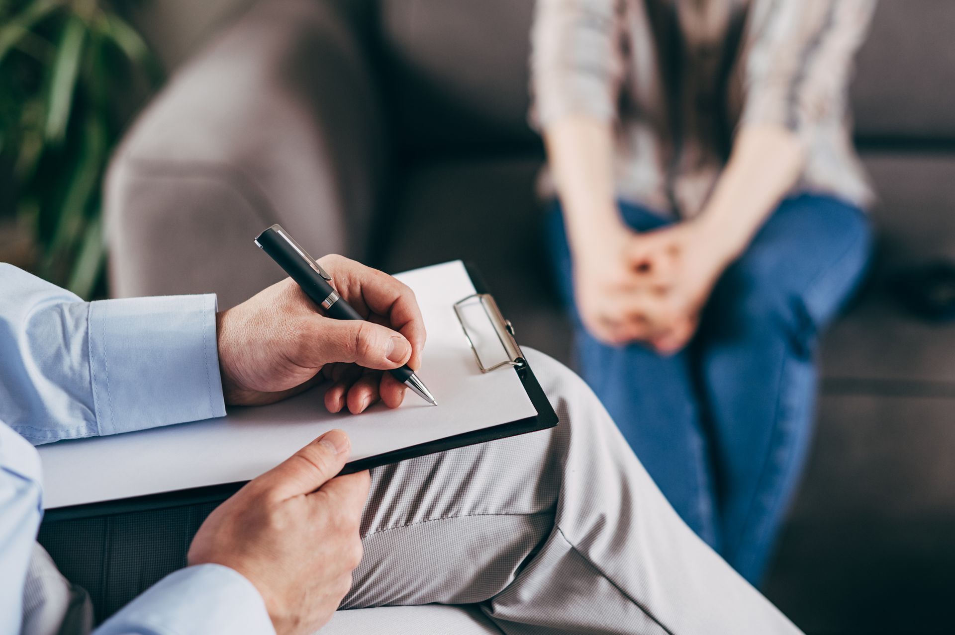 Terapeuta prende appunti durante una seduta con un cliente seduto su un divano.