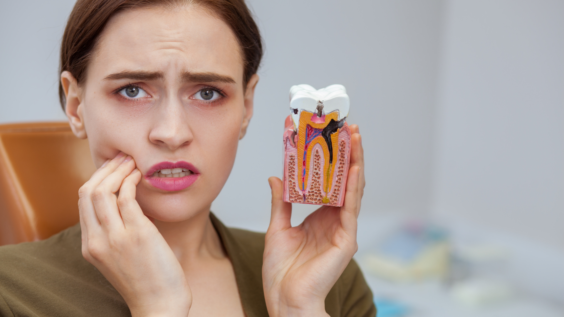 A woman is holding a model of a tooth with a toothache.