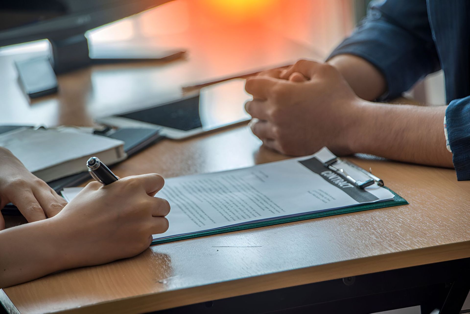 Person Is Writing On A Clipboard While Sitting At A Table — Michael Andrews Taxation & Accounting Services In Caloundra, QLD