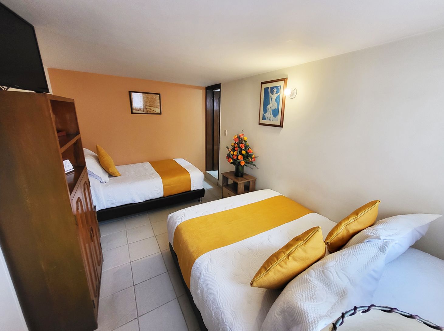 Two beds with white sheets and yellow accents in a hotel room.