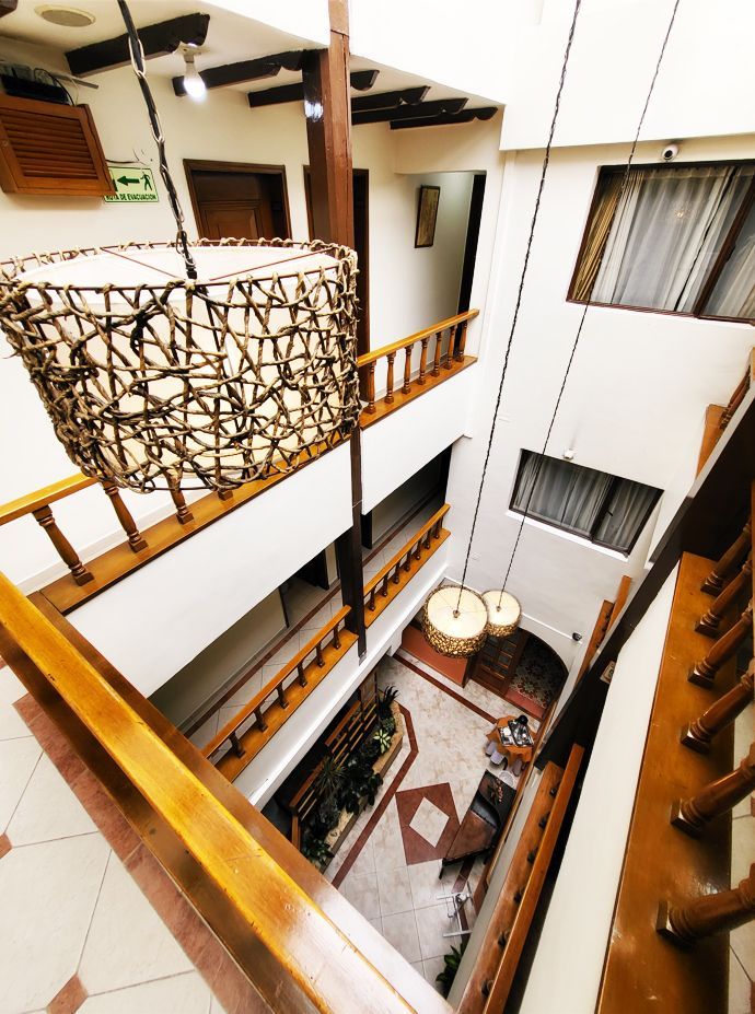 Multi-story interior with wooden railings, hanging lamps, and a light-filled atrium.