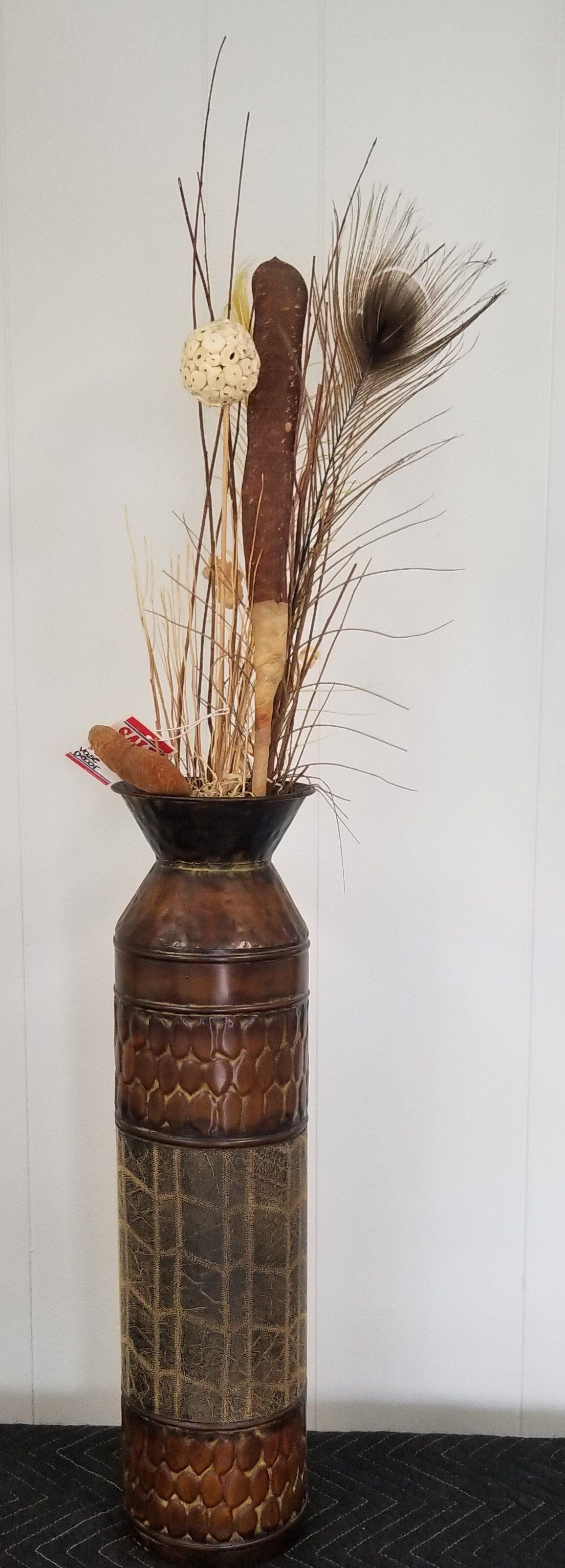 Brown metal vase with sticks and foliage.