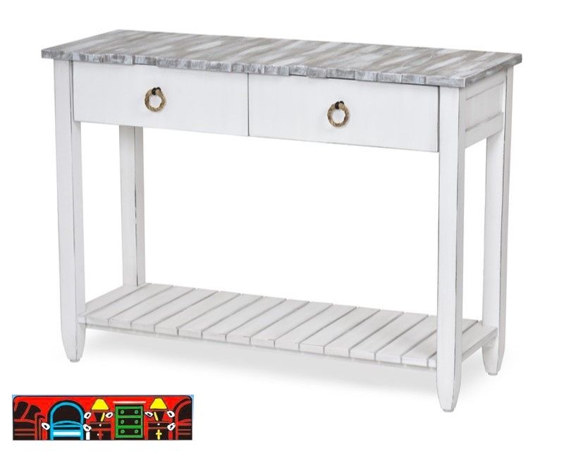 The Picket Fence Sofa Table offers a coastal charm with its solid wood construction, distressed white finish, weathered grey top, and rope pulls. Available at Bratz-CFW.