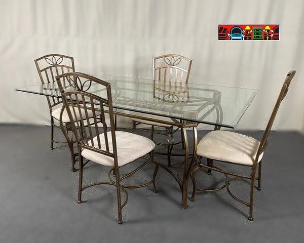 'A gently used dining set featuring a glass top and four side chairs, complemented by a gold metal base and chairs with light upholstery.'
