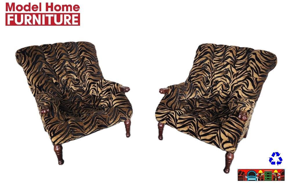 'A model-home set of club chairs featuring tufted fabric with a tiger stripe pattern, and exposed wooden legs and arm caps.'