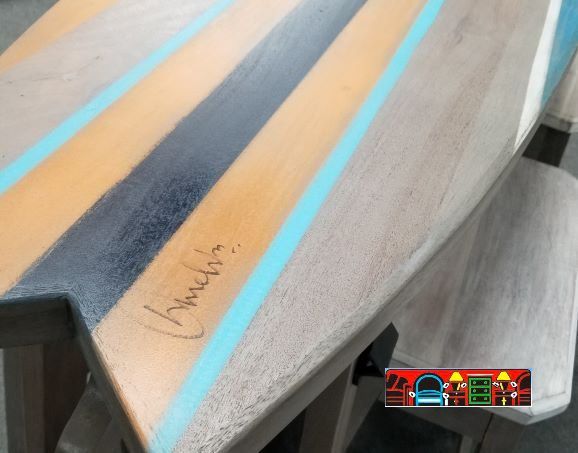 A pub dining hand-painted striped top, signed by the artisan who crafted the surfboard-shaped table.
