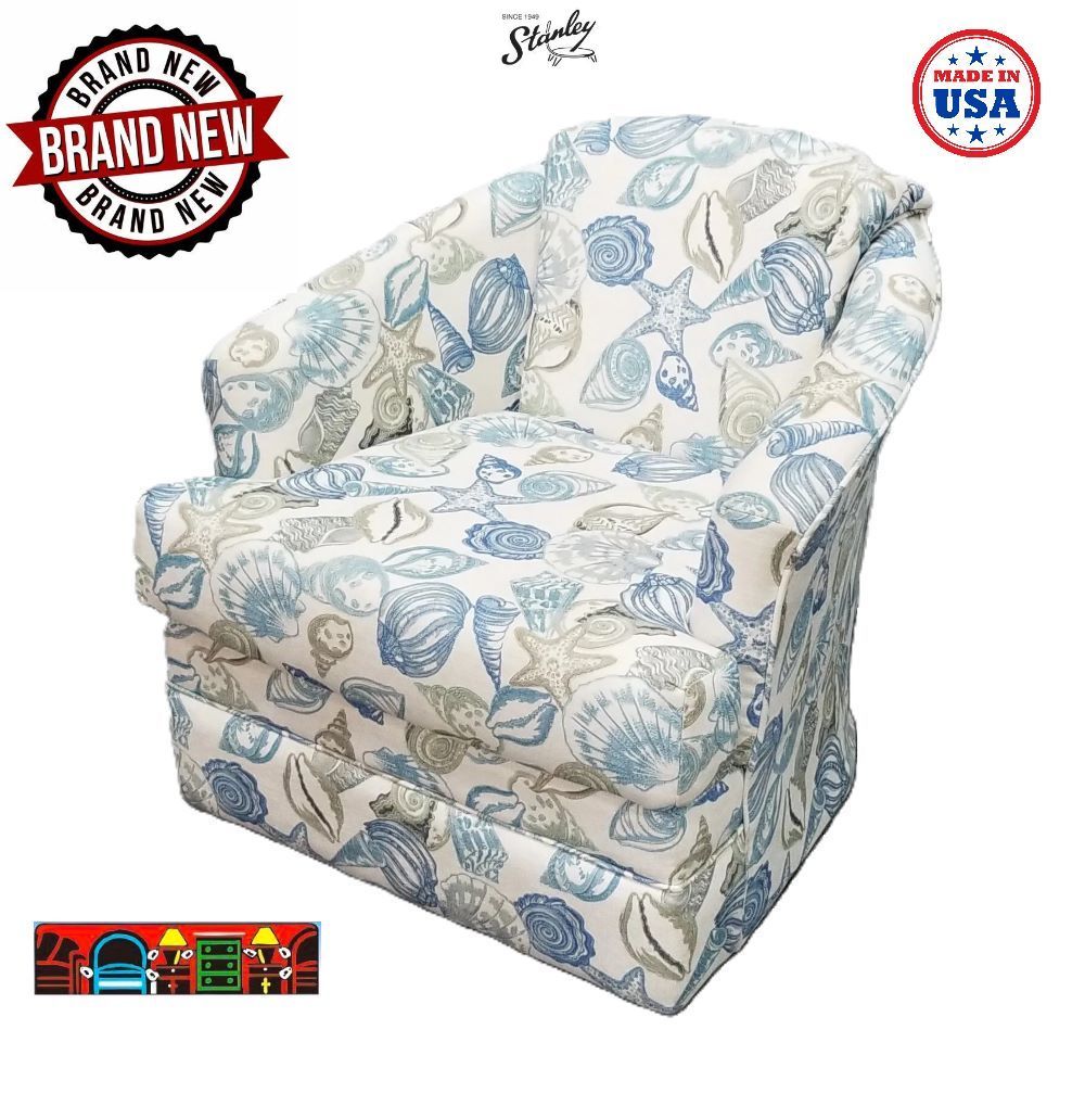 'A coastal barrel chair featuring a reversible cushion set against a white background, adorned with blue and beige shell patterns throughout.'