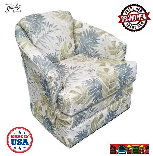 'An American made tropical-style barrel chair featuring a reversible cushion set against an off-white background, adorned with green leaves and two shades of grey.'