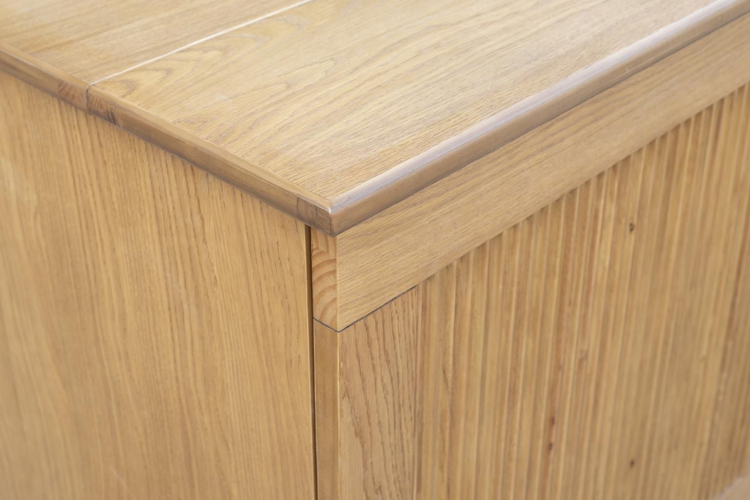 Oak finish cabinet bed with a decorative pencil wood design and 2 large wood handles. with a drawer at the bottom. Close-up view.