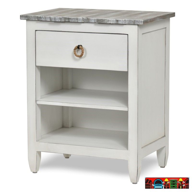 The Picket Fence Bedroom Nightstand offers a coastal charm with its solid wood construction, distressed white finish, weathered grey top, and rope pull. Available at Bratz-CFW.